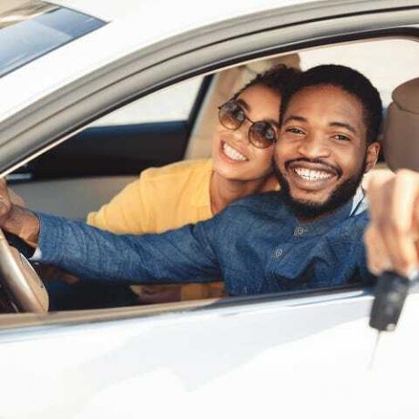 afroamerickí manželia ukazujúci nový kľúč od auta sediaci v aute