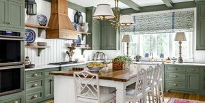 kuchyňa s upokojujúcimi zelenými maľovanými skrinkami, krokvami a obložením v kombinácii s bielymi obloženými stenami, stropom a ostrovčekom