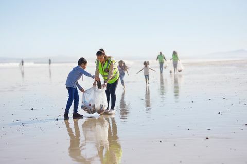 Matka a syn dobrovoľne čistia odpadky na slnečnej a vlhkej piesočnatej pláži