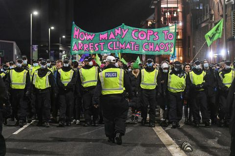 glasgow, škótsko november 03 policajní dôstojníci sprevádzajú protest proti vyhynutiu pred summitom cop26, keď je vidieť transparent s nápisom, koľko policajtov má zatknúť klimatický chaos na 3. novembra 2021 v Glasgowe v Spojenom kráľovstve, keď sa svetoví lídri stretávajú, aby diskutovali o zmene klímy na samite cop26, mnohé skupiny klimatických opatrení vyšli do ulíc protestovať za skutočný pokrok, ktorý majú vlády dosiahnuť pri znižovaní emisií uhlíka, čistení oceánov, znižovaní spotreby fosílnych palív a iných otázkach týkajúcich sa globálneho vykurovania foto peter summersgetty snímky