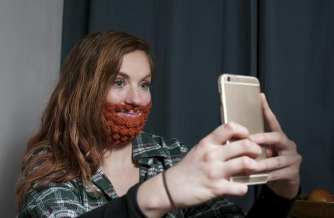 žena s červenou háčkovanou bradou, ktorá si robí selfie na deň svätého Patrika