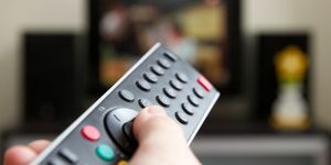 ľudská ruka drží diaľkové ovládanie prepínanie kanálov s televízorom