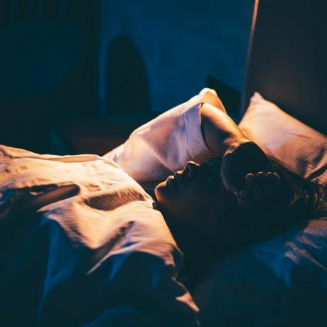 žena s nespavosťou mladá žena ležiaca na posteli s rukou na čele