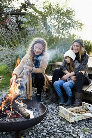 dve ženy a dievča sedia pri ohnisku a relaxujú