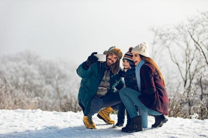 rodina si robí selfie počas zimného dňa v zasneženom lese