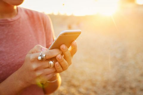 Žena drží mobilný telefón na pláži