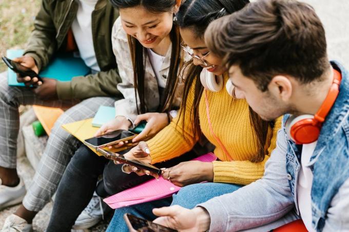 Rôznorodí mladí dospievajúci študenti, ktorí sa zabávajú používaním mobilného telefónu vo vzdelávaní na univerzite, ľudia z tisícročia a koncept sociálnych médií