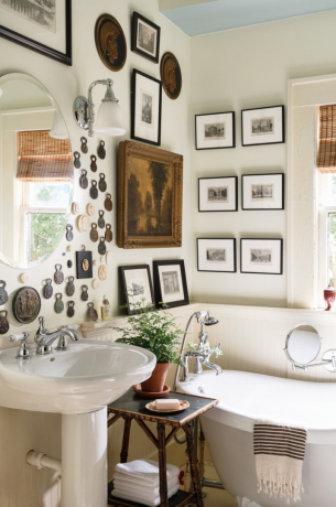 zhromaždená kúpeľňa s vintage umením na stene a vaňou s pazúrikovou nohou