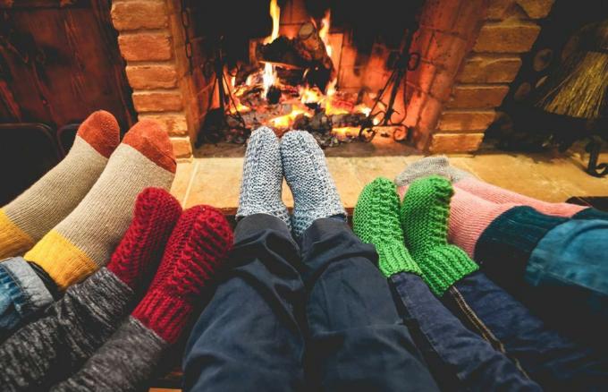 nohy pohľad na šťastnú rodinu, ktorá nosí teplé ponožky pred krbom zima, láska a útulný koncept sa zamerajú na stredové sivé vlnené ponožky