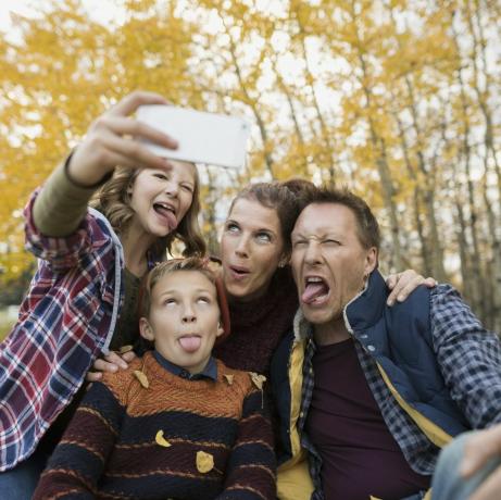 Hlúpa rodinka, ktorá si robí selfie tvár v jesennom parku